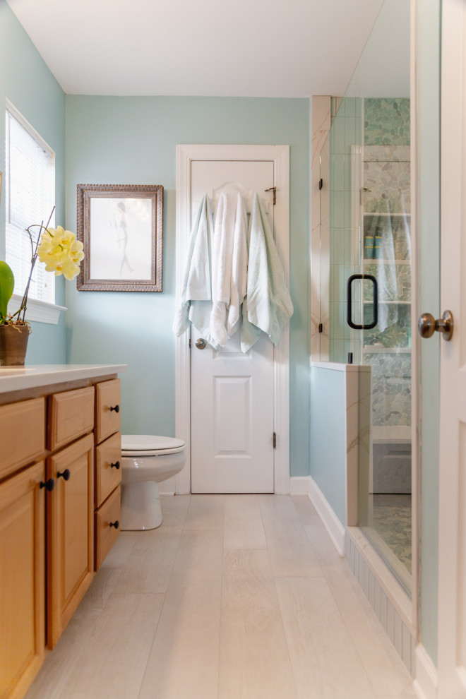 Cette photo montre une petite douche en alcôve principale bord de mer en bois clair avec un placard avec porte à panneau surélevé, WC séparés, un carrelage vert, des carreaux de porcelaine, un mur vert, un sol en carrelage de porcelaine, un lavabo encastré, un plan de toilette en quartz modifié, un sol beige, une cabine de douche à porte battante, un plan de toilette blanc, un banc de douche, meuble simple vasque et meuble-lavabo encastré.