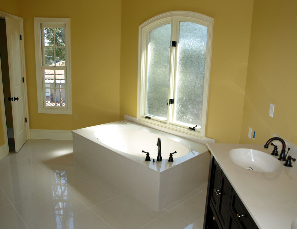 Пример оригинального дизайна: главная ванная комната среднего размера в классическом стиле с фасадами с утопленной филенкой, черными фасадами, накладной ванной, желтыми стенами, полом из керамогранита, монолитной раковиной, столешницей из искусственного кварца и белым полом