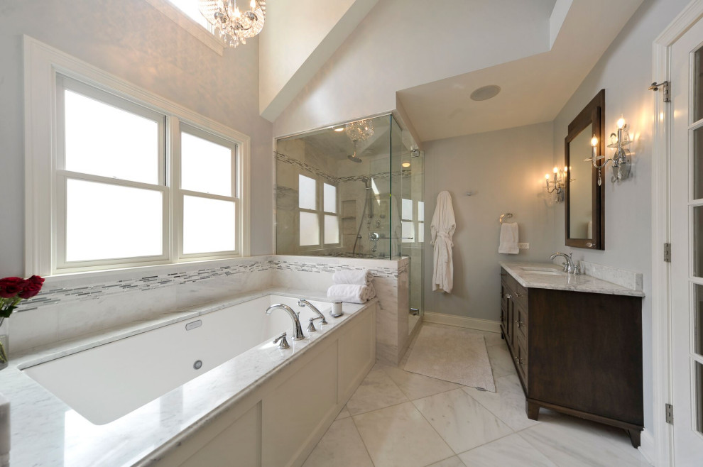 Aménagement d'une grande salle de bain principale classique en bois foncé avec un placard à porte affleurante, un bain bouillonnant, une douche d'angle, un carrelage gris, du carrelage en marbre, un mur gris, un sol en marbre, un plan de toilette en marbre, une cabine de douche à porte battante et un plan de toilette blanc.