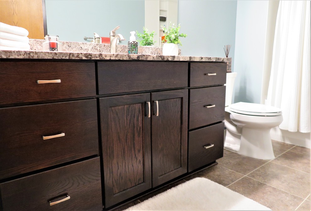 Alcove bathtub - mid-sized transitional master white tile vinyl floor and brown floor alcove bathtub idea in Minneapolis with recessed-panel cabinets, dark wood cabinets, a two-piece toilet, blue walls, an undermount sink, granite countertops and gray countertops