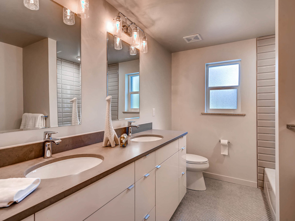 Example of a trendy bathroom design in Denver with flat-panel cabinets, white cabinets, a two-piece toilet, beige walls and an undermount sink