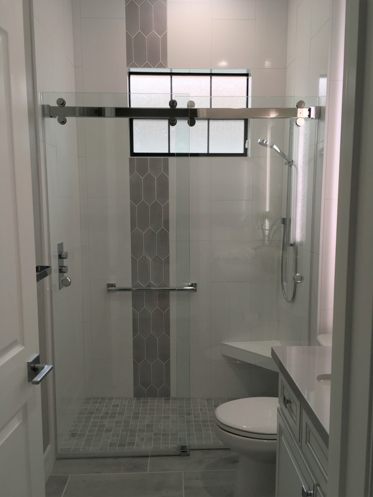 Inspiration for a mid-sized modern 3/4 porcelain tile and gray floor bathroom remodel in Tampa with recessed-panel cabinets, white cabinets, a two-piece toilet, gray walls, an undermount sink, quartz countertops and gray countertops