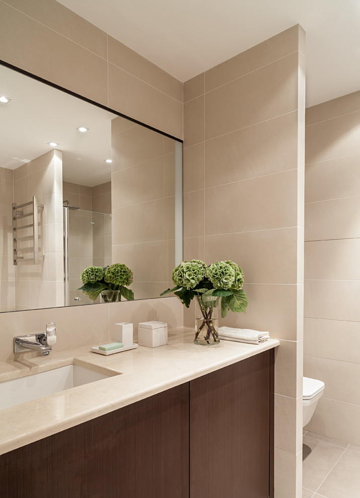 Свежая идея для дизайна: ванная комната в современном стиле с врезной раковиной, плоскими фасадами, темными деревянными фасадами и бежевой плиткой - отличное фото интерьера