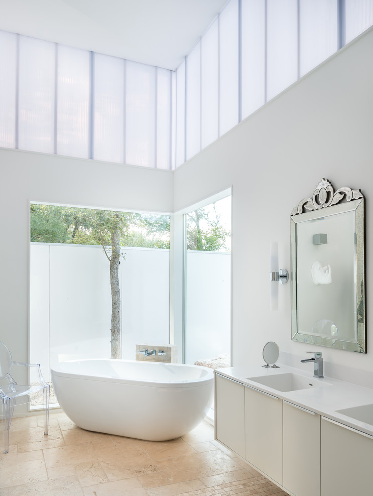 Идея дизайна: главная ванная комната в современном стиле с монолитной раковиной, плоскими фасадами, белыми фасадами, столешницей из искусственного камня, отдельно стоящей ванной, белыми стенами и полом из травертина