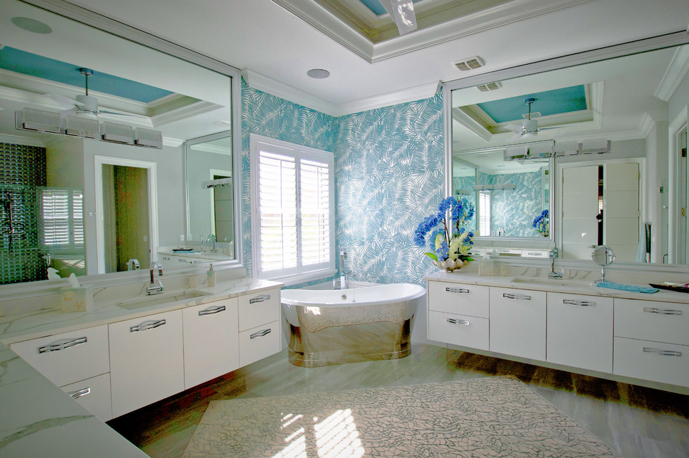 Großes Modernes Badezimmer En Suite mit flächenbündigen Schrankfronten, weißen Schränken, freistehender Badewanne, bodengleicher Dusche, weißen Fliesen, blauer Wandfarbe, integriertem Waschbecken, Granit-Waschbecken/Waschtisch, weißem Boden, Falttür-Duschabtrennung und weißer Waschtischplatte in Miami