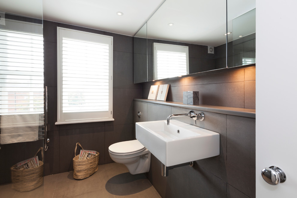 Inspiration for a medium sized modern family bathroom in London with a wall-mounted sink, concrete worktops, a walk-in shower, a wall mounted toilet, grey tiles, cement tiles, grey walls and slate flooring.
