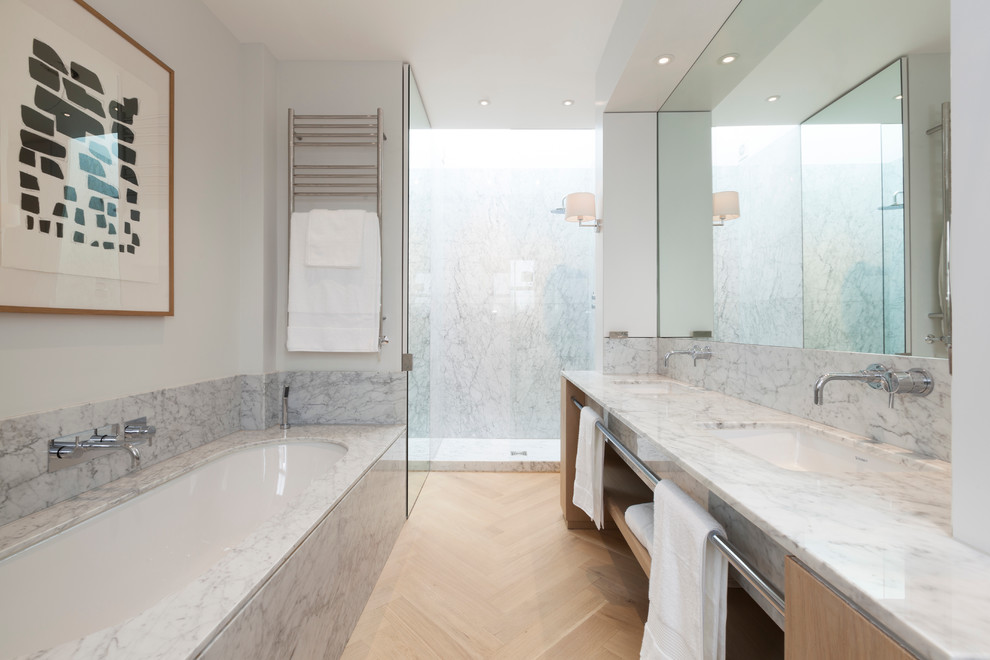This is an example of a medium sized modern ensuite bathroom in London with a submerged sink, open cabinets, medium wood cabinets, marble worktops, a built-in bath, a walk-in shower, a wall mounted toilet, white walls and medium hardwood flooring.