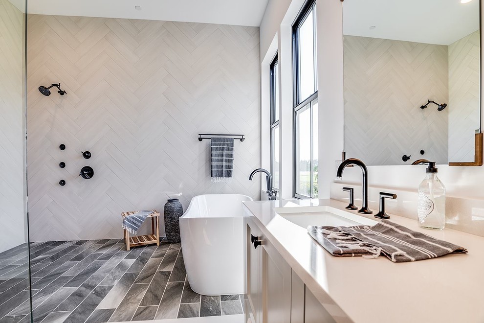 Lantlig inredning av ett stort vit vitt en-suite badrum, med luckor med infälld panel, grå skåp, ett fristående badkar, vita väggar och ett undermonterad handfat