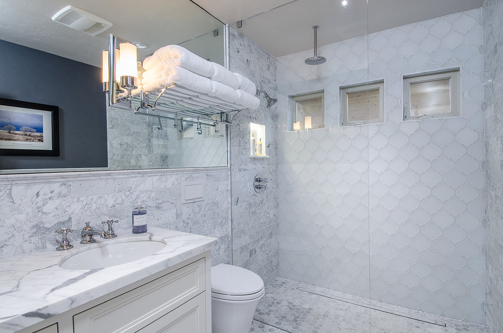 Modelo de cuarto de baño clásico con lavabo bajoencimera, armarios con paneles empotrados, puertas de armario blancas, ducha a ras de suelo, baldosas y/o azulejos blancos y suelo con mosaicos de baldosas