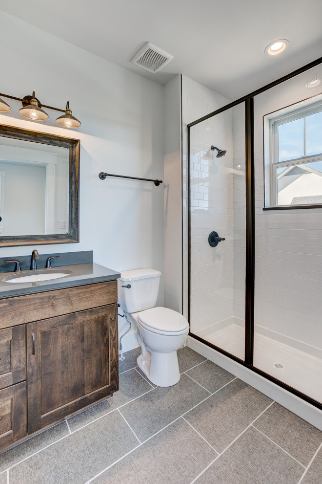 This is an example of a medium sized country ensuite bathroom in Denver with a freestanding bath, a walk-in shower, a one-piece toilet, white tiles, metro tiles, white walls, ceramic flooring, a submerged sink, grey floors and a hinged door.