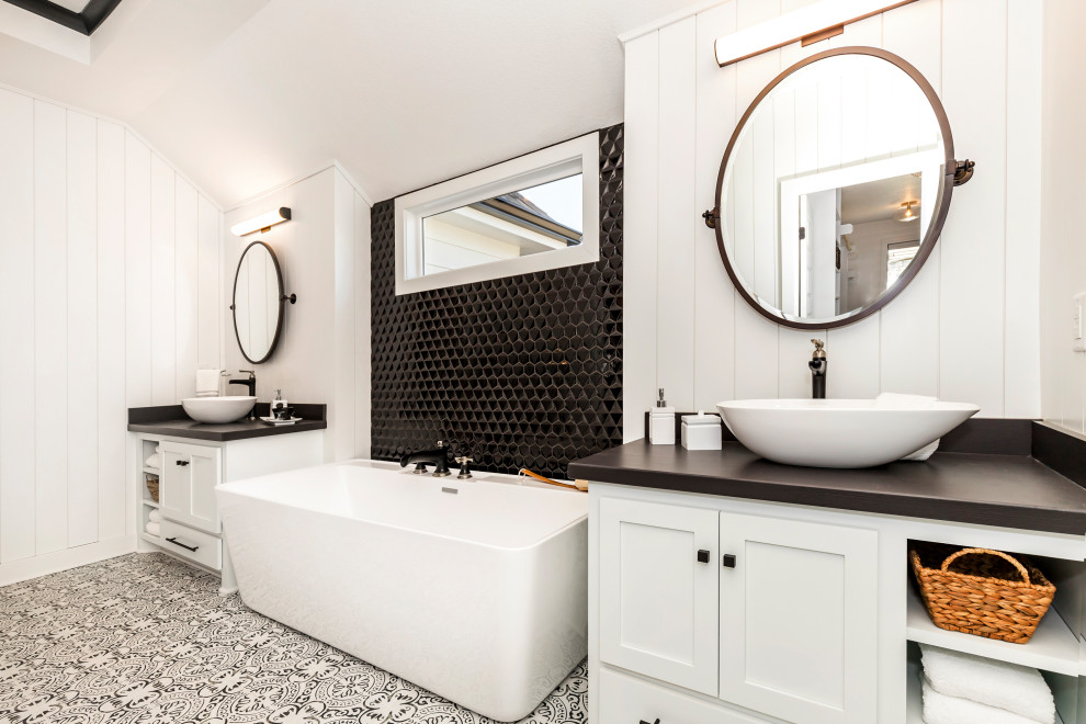 Large farmhouse ensuite bathroom in Kansas City with shaker cabinets, white cabinets, a freestanding bath, a double shower, a one-piece toilet, black and white tiles, mosaic tiles, white walls, porcelain flooring, a pedestal sink, granite worktops, white floors, a hinged door and black worktops.