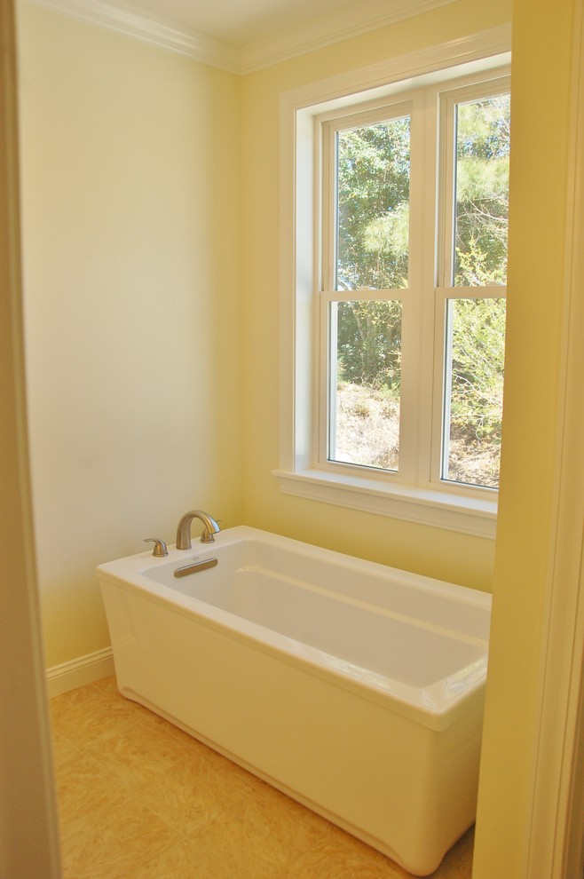 Maritim inredning av ett mellanstort badrum med dusch, med ett fristående badkar, gula väggar, klinkergolv i keramik och beiget golv