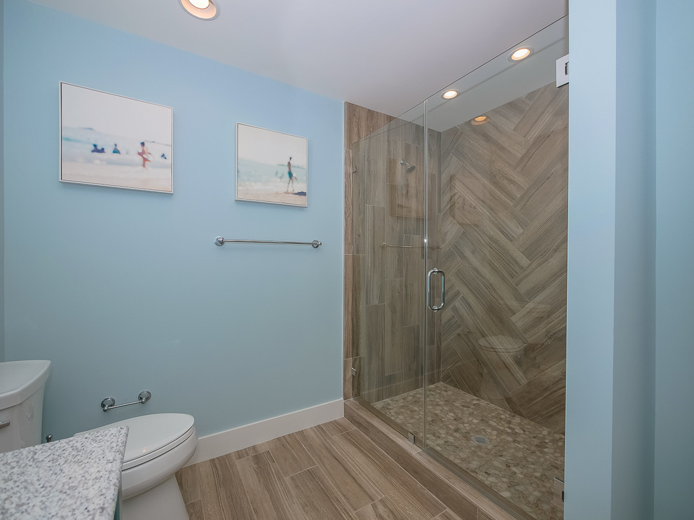 На фото: ванная комната среднего размера в морском стиле с фасадами островного типа, синими фасадами, душем в нише, бежевой плиткой, керамогранитной плиткой, коричневыми стенами, полом из керамогранита, душевой кабиной, врезной раковиной, столешницей из искусственного кварца, бежевым полом и душем с распашными дверями с