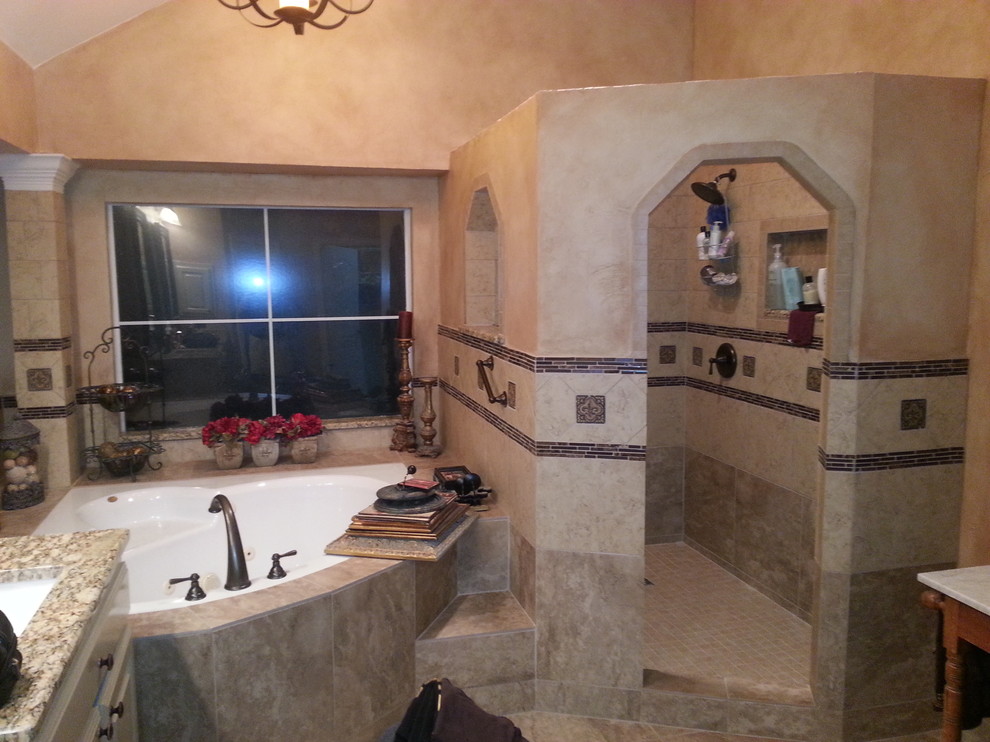 Cette image montre une grande salle de bain principale chalet avec un lavabo encastré, un placard avec porte à panneau surélevé, des portes de placard blanches, un plan de toilette en granite, une baignoire d'angle, une douche d'angle, un carrelage beige, des carreaux de porcelaine et un mur beige.