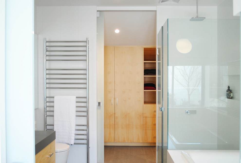 Photo of a small contemporary ensuite bathroom in Melbourne with flat-panel cabinets, light wood cabinets, a corner shower, a two-piece toilet, white tiles, ceramic tiles, white walls, porcelain flooring, a built-in sink, engineered stone worktops and a hinged door.
