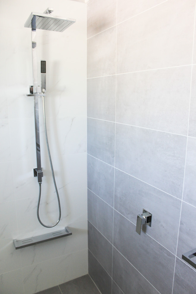 Photo of a large modern shower room bathroom in Perth with flat-panel cabinets, white cabinets, a walk-in shower, a one-piece toilet, white tiles, porcelain tiles, grey walls, porcelain flooring, an integrated sink, glass worktops, grey floors, an open shower and white worktops.