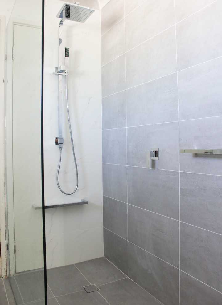 Large minimalist 3/4 white tile and porcelain tile porcelain tile and gray floor bathroom photo in Perth with flat-panel cabinets, white cabinets, a one-piece toilet, gray walls, an integrated sink, glass countertops and white countertops