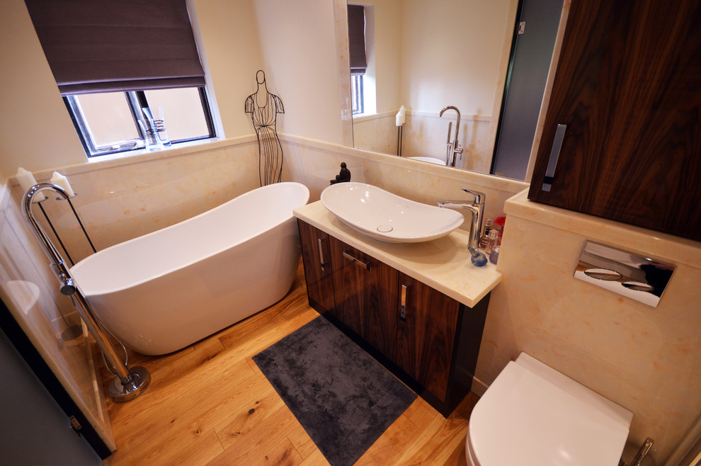 Bathroom - mid-sized contemporary master light wood floor bathroom idea in Manchester with furniture-like cabinets, dark wood cabinets, a wall-mount toilet, a vessel sink and quartz countertops