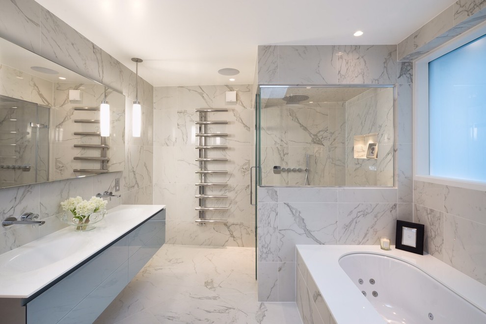 На фото: главная ванная комната в современном стиле с подвесной раковиной, плоскими фасадами, гидромассажной ванной и мраморной плиткой с