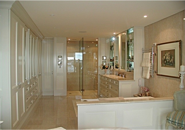 Inredning av ett klassiskt mellanstort badrum, med ett nedsänkt handfat, luckor med infälld panel, beige skåp, marmorbänkskiva, en dusch i en alkov, en toalettstol med hel cisternkåpa, beige kakel, stenkakel, beige väggar och marmorgolv