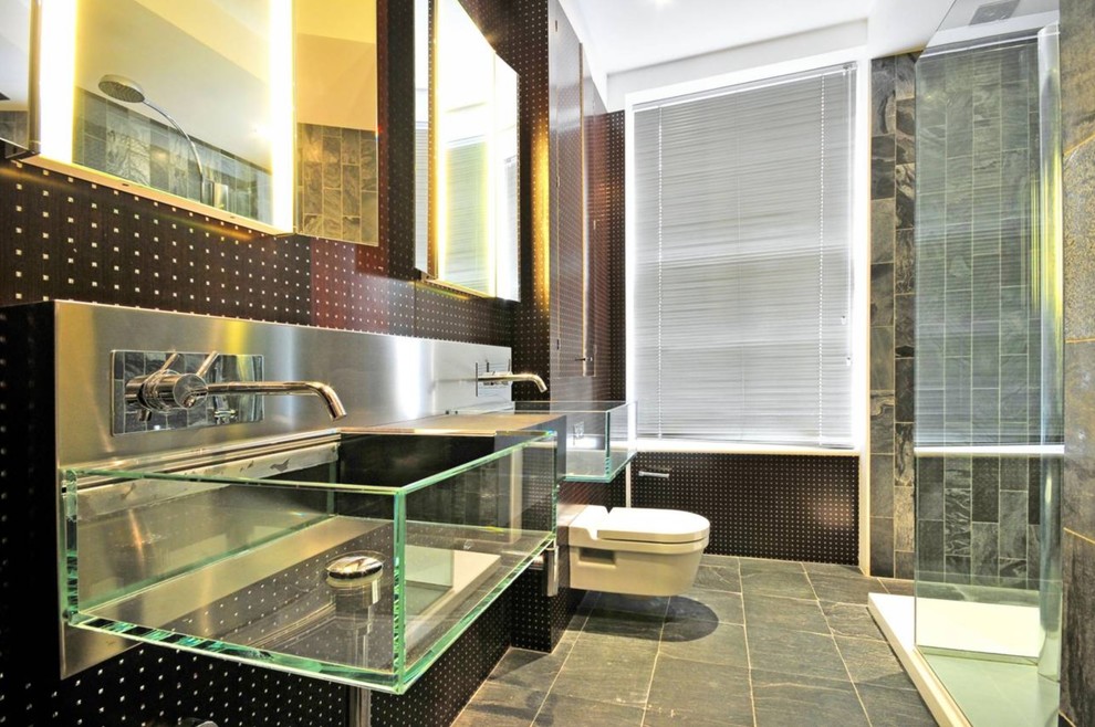 This is an example of a medium sized urban bathroom in London with a wall mounted toilet, a wall-mounted sink, grey floors, a corner shower, grey tiles and black walls.