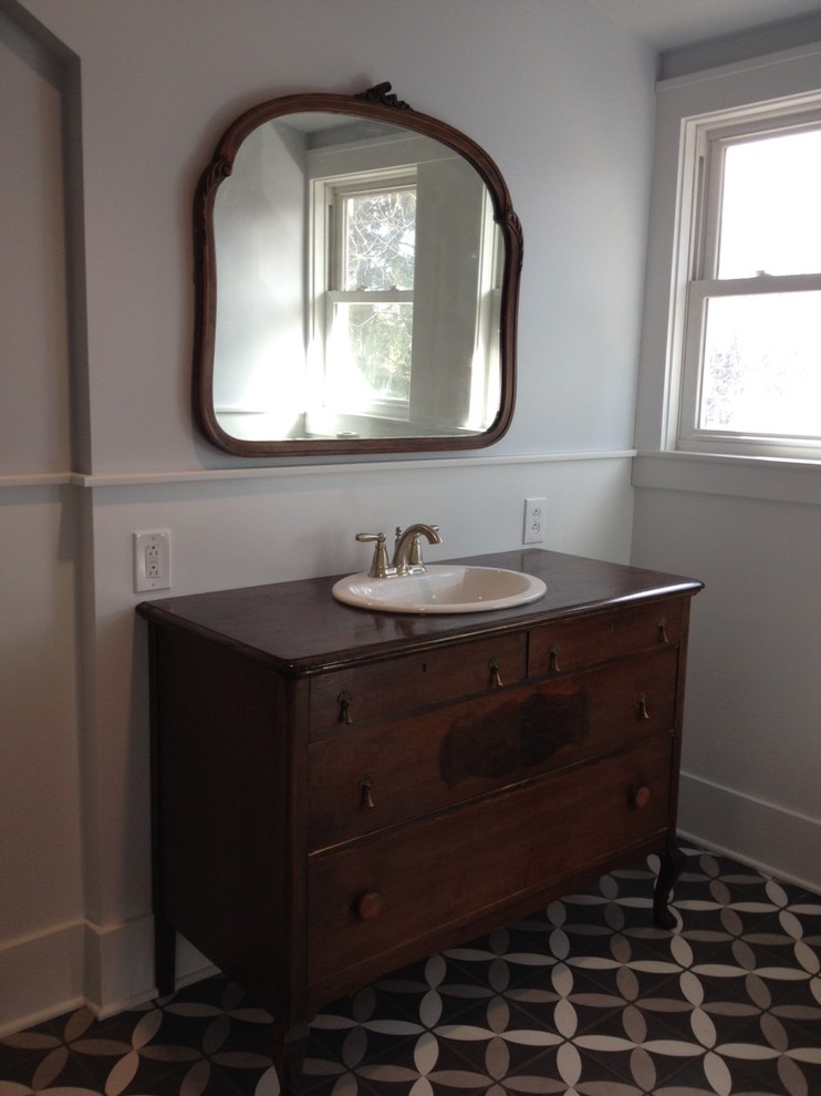 Cette photo montre une salle de bain principale éclectique en bois brun de taille moyenne avec un placard en trompe-l'oeil, WC à poser, un mur gris, un sol en carrelage de céramique, un lavabo posé, un plan de toilette en bois et un sol gris.