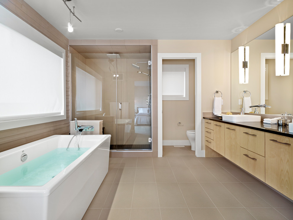 Идея дизайна: главная ванная комната в современном стиле с плоскими фасадами, светлыми деревянными фасадами, отдельно стоящей ванной, накладной раковиной, душем с распашными дверями и черной столешницей