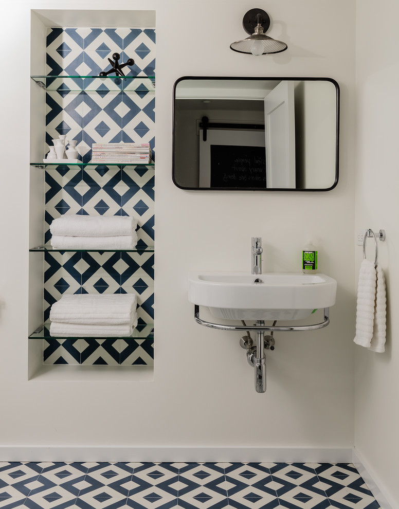 Cette image montre une petite salle de bain minimaliste avec WC à poser, un carrelage bleu, des carreaux de béton, un mur blanc, carreaux de ciment au sol, un lavabo suspendu, un sol bleu et une cabine de douche à porte battante.