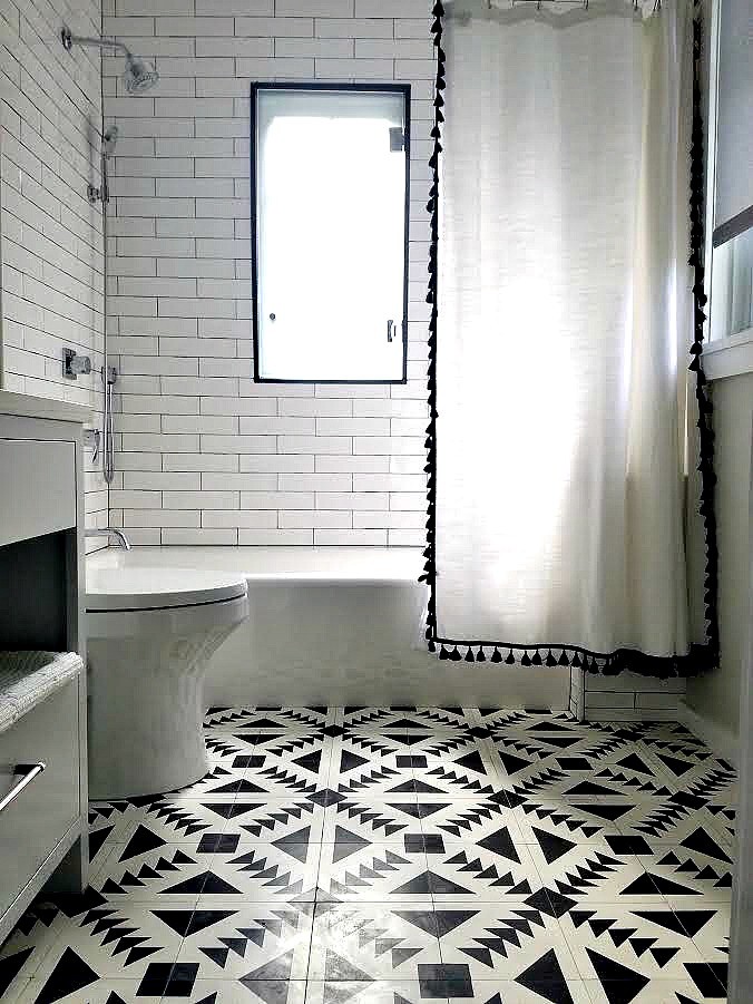Design ideas for a medium sized modern bathroom in New York with flat-panel cabinets, grey cabinets, an alcove bath, a shower/bath combination, a one-piece toilet, white tiles, cement tiles, white walls, cement flooring, a submerged sink, quartz worktops, black floors and a shower curtain.