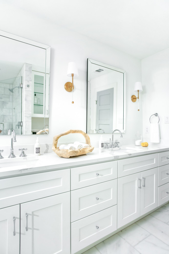 Exemple d'une salle de bain bord de mer avec un placard à porte shaker, des portes de placard blanches, un mur blanc, un lavabo encastré, un sol blanc, un plan de toilette blanc, meuble double vasque et meuble-lavabo encastré.