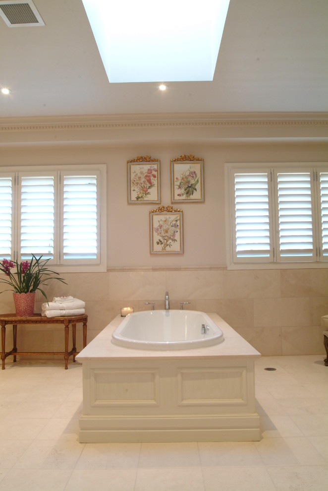 Ispirazione per una grande stanza da bagno classica con vasca da incasso, piastrelle beige, pareti beige e pavimento beige