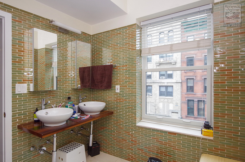 Mittelgroßes Badezimmer En Suite mit offenen Schränken, braunen Schränken, farbigen Fliesen, Glasfliesen, grüner Wandfarbe, Waschtisch aus Holz, beigem Boden und brauner Waschtischplatte in New York