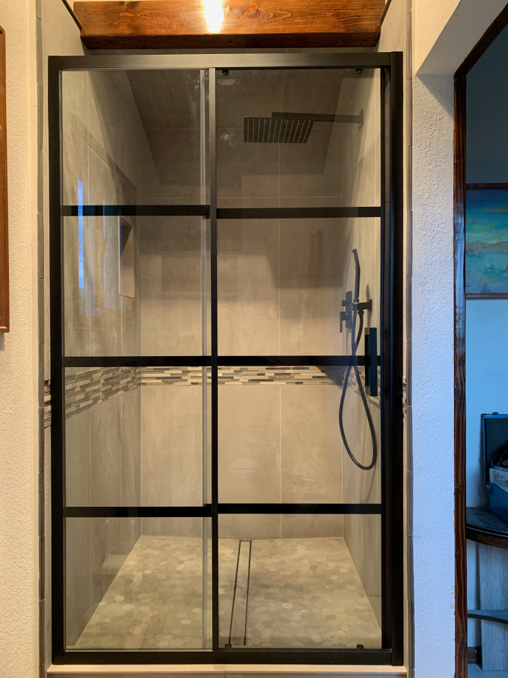 Klassisk inredning av ett mellanstort badrum, med en dusch i en alkov, grå kakel, porslinskakel, grå väggar, klinkergolv i småsten, grått golv och dusch med skjutdörr