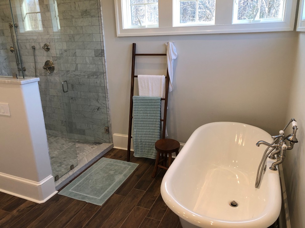 Design ideas for a large contemporary ensuite bathroom in Philadelphia with flat-panel cabinets, white cabinets, a corner shower, a one-piece toilet, grey tiles, stone tiles, grey walls, medium hardwood flooring, a console sink, granite worktops, brown floors, a hinged door, grey worktops and a freestanding bath.