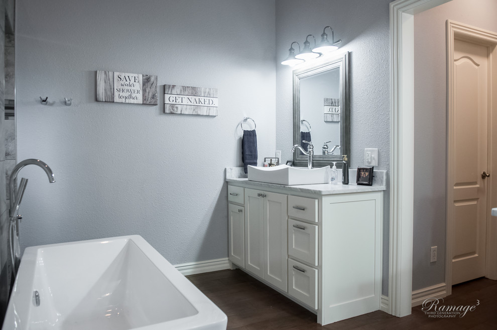 Idéer för att renovera ett stort vintage vit vitt en-suite badrum, med skåp i shakerstil, vita skåp, ett fristående badkar, en dubbeldusch, grå kakel, porslinskakel, grå väggar, klinkergolv i porslin, ett fristående handfat, granitbänkskiva, brunt golv och med dusch som är öppen