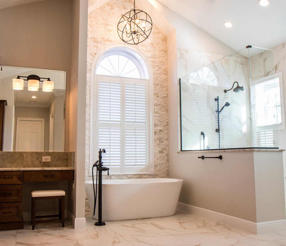Inredning av ett klassiskt stort grå grått en-suite badrum, med luckor med infälld panel, skåp i mellenmörkt trä, ett fristående badkar, en kantlös dusch, grå kakel, porslinskakel, grå väggar, klinkergolv i porslin, ett undermonterad handfat, granitbänkskiva, grått golv och med dusch som är öppen