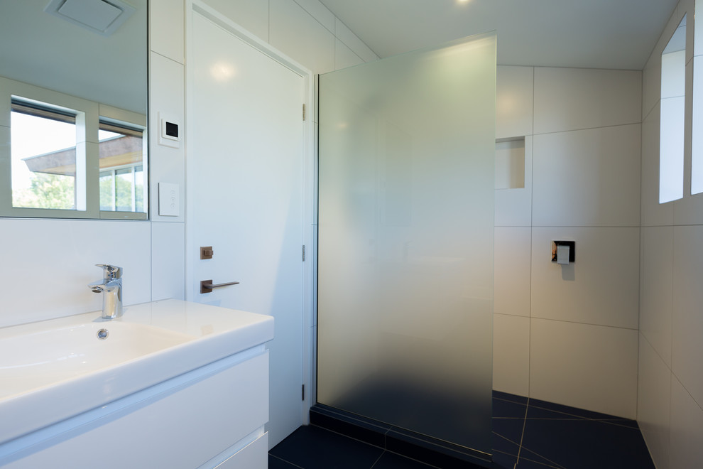 На фото: детская ванная комната в современном стиле с белыми фасадами, накладной ванной, душем в нише, белой плиткой, керамической плиткой, белыми стенами, полом из керамической плитки, подвесной раковиной, синим полом и открытым душем с