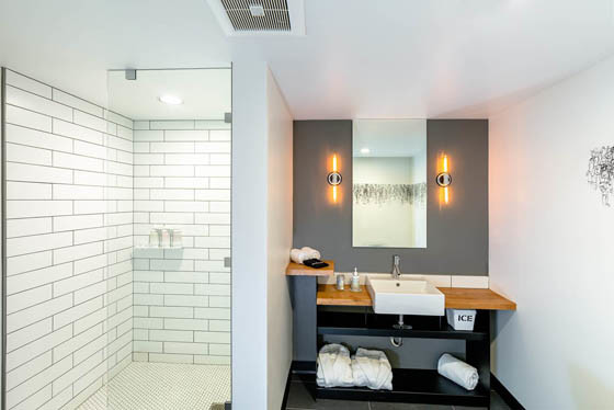 Exemple d'une salle de bain principale moderne avec une vasque, des portes de placard noires, un plan de toilette en bois, une douche d'angle, un carrelage blanc, un carrelage métro, un mur gris et un sol en ardoise.