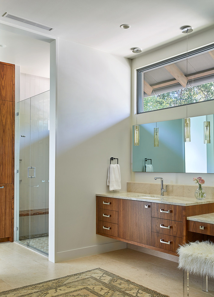 Example of an urban master limestone floor and beige floor bathroom design in Austin with flat-panel cabinets, medium tone wood cabinets, white walls and quartzite countertops