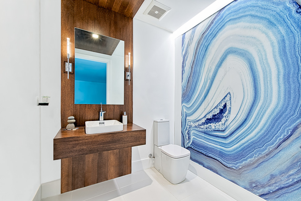 Mittelgroßes Modernes Duschbad mit Wandtoilette mit Spülkasten, Aufsatzwaschbecken, Waschtisch aus Holz, blauer Wandfarbe, offenen Schränken, hellbraunen Holzschränken und Porzellan-Bodenfliesen in Miami