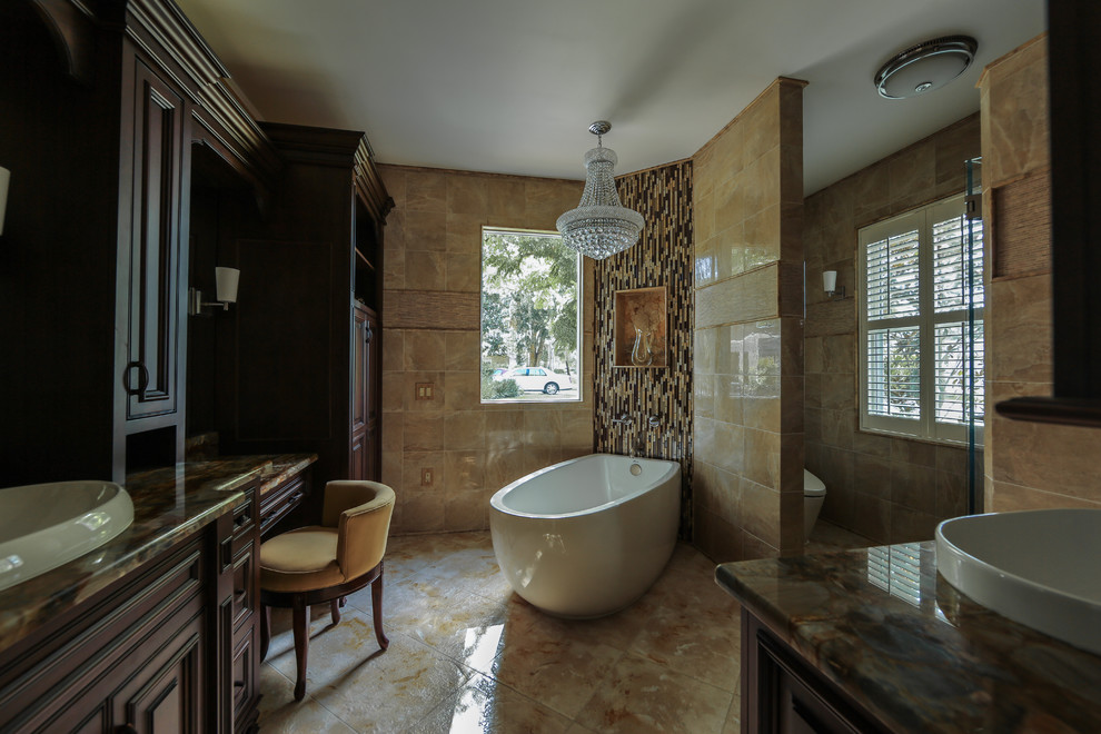 Cette photo montre une salle de bain principale chic en bois foncé avec un placard à porte affleurante, une baignoire indépendante, une douche d'angle, un carrelage beige, un carrelage noir, un mur beige, un lavabo posé, un plan de toilette en granite, un sol beige et une cabine de douche à porte battante.