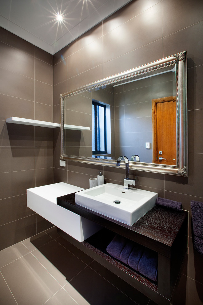 Inspiration för mellanstora moderna badrum, med ett fristående handfat, skåp i mellenmörkt trä, bänkskiva i kvarts, ett fristående badkar och grå kakel