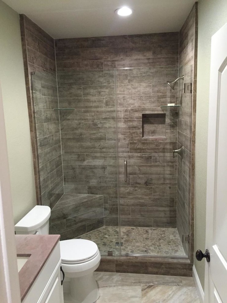 Inredning av ett modernt litet badrum med dusch, med luckor med upphöjd panel, vita skåp, en dusch i en alkov, en toalettstol med separat cisternkåpa, grå kakel, stenkakel, ett undermonterad handfat och bänkskiva i akrylsten