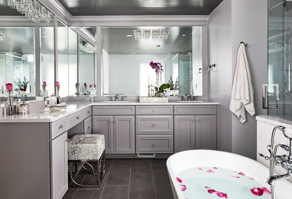 Inspiration for a large classic ensuite bathroom in Chicago with recessed-panel cabinets, grey cabinets, a freestanding bath, a two-piece toilet, white tiles, porcelain tiles, grey walls, porcelain flooring, a submerged sink, engineered stone worktops, grey floors, white worktops and double sinks.