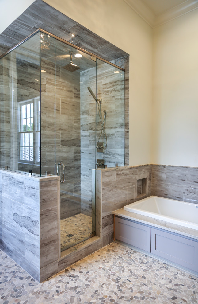 Photo of a traditional bathroom in New Orleans with a built-in bath, a corner shower, grey tiles, white walls, pebble tile flooring, white floors, a hinged door and a vaulted ceiling.