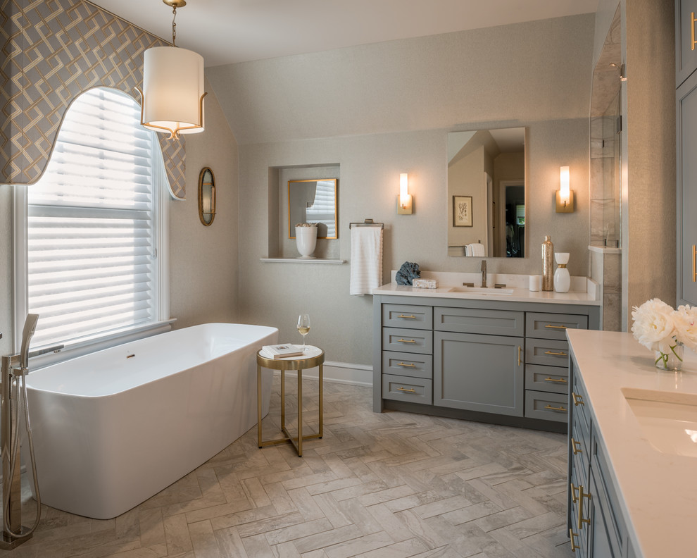 Klassisk inredning av ett en-suite badrum, med skåp i shakerstil, grå skåp, ett fristående badkar, grå väggar och ett undermonterad handfat