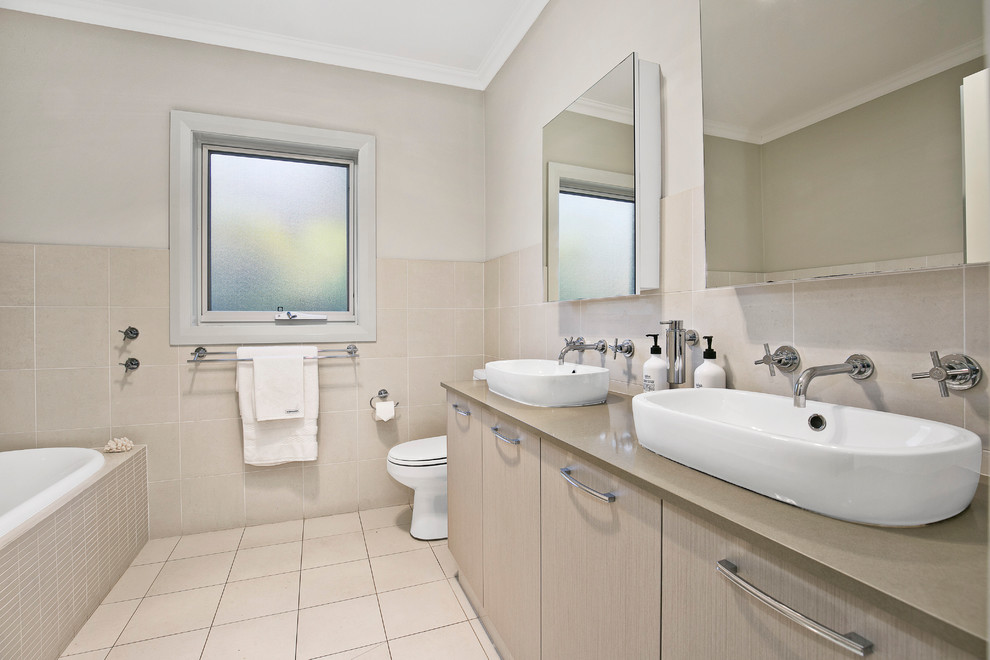 Idee per una stanza da bagno per bambini design di medie dimensioni con vasca da incasso, WC monopezzo, piastrelle beige e pareti beige
