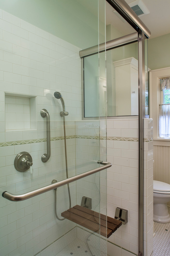 Inredning av ett amerikanskt litet badrum, med ett piedestal handfat, en dubbeldusch, vit kakel, tunnelbanekakel, gröna väggar, mosaikgolv, luckor med profilerade fronter, vita skåp och en toalettstol med separat cisternkåpa