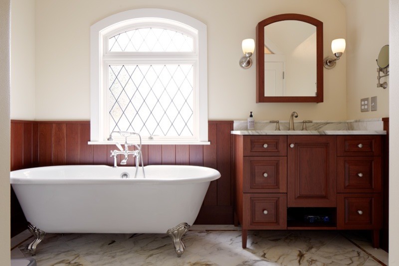 Foto på ett stort vintage en-suite badrum, med ett undermonterad handfat, möbel-liknande, skåp i mörkt trä, marmorbänkskiva, ett badkar med tassar, en öppen dusch, en toalettstol med separat cisternkåpa, vit kakel, stenkakel, beige väggar och marmorgolv