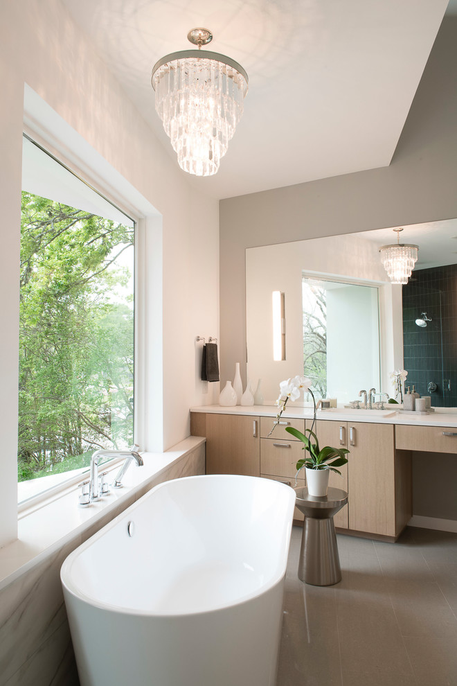 Inspiration for a medium sized contemporary ensuite bathroom in Austin with flat-panel cabinets, light wood cabinets, a freestanding bath, a built-in shower, a one-piece toilet, a submerged sink, solid surface worktops, grey floors, a hinged door and white worktops.
